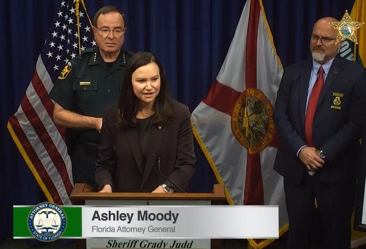 Florida Attorney General Ashley Moody addresses reporters about a statewide theft ring, with Polk County Sheriff Grady Judd, left, and Michael Giddens, right, an FDLE supervisor out of Orlando.