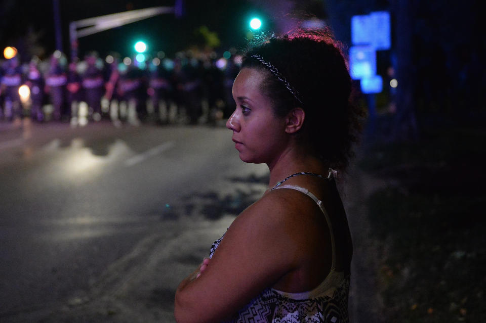 A woman watches as law enforcement officers secure an area during a protest action following a "not guilty" verdict for former police Officer Jason Stockley on Sept. 15, 2017, in St. Louis. Stockley was charged with first-degree murder last year in the 2011 shooting death of motorist Anthony Lamar Smith.