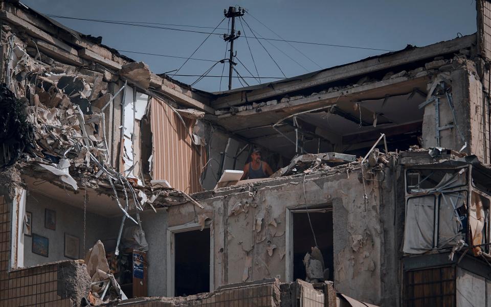 A man cleans an apartment destroyed after Russian shelling in Nikopol - AP