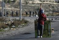 A masked Palestinian protester gestures during clashes with Israeli troops in the West Bank city of Ramallah on December 8, 2017