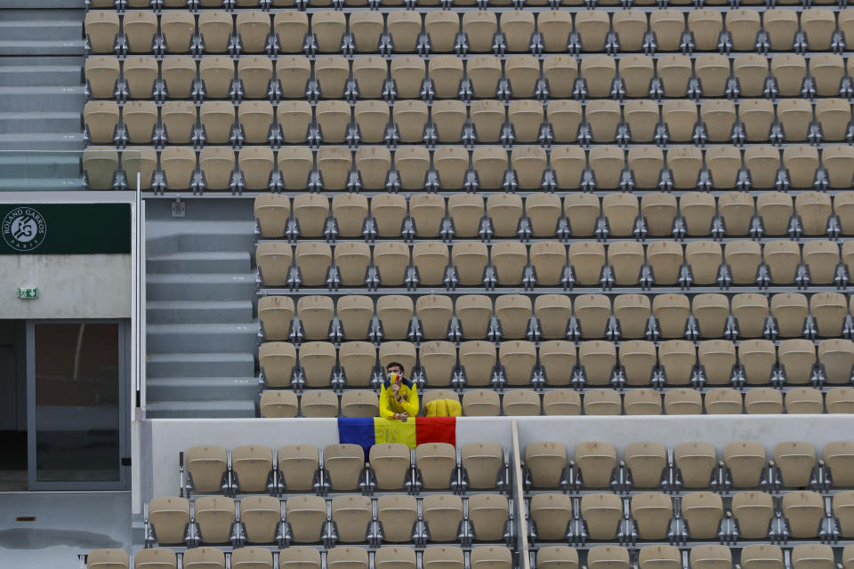 A lone fan with the Romanian flag and a face mask in the colors of the flag watches Romania's Simona Halep and Romania's Irina-Camelia Begu's second round match of the French Open tennis tournament in Suzanne Lenglen court at the Roland Garros stadium in Paris, France, Wednesday, Sept. 30, 2020. (AP Photo/Alessandra Tarantino)