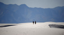 In this Thursday, March 5, 2020, photograph, a couple walks over gypsum dunes in White Sands National Park at Holloman Air Force Base, N.M. With the new coronavirus changing how people navigate their lives, folks have looked to the great outdoors for exercise and entertainment in these turbulent times. The new coronavirus causes mild or moderate symptoms for most people, but for some, especially older adults and people with existing health problems, it can cause more severe illness or death. (AP Photo/David Zalubowski)