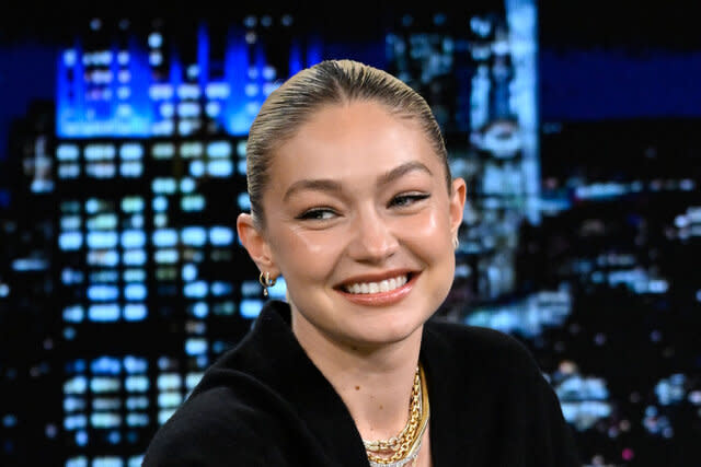 Gigi smiling in front of a cityscape.