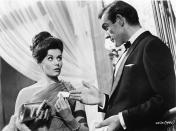 Scottish actor Sean Connery, as fictional secret agent James Bond, hands a business card to British actress Eunice Gayson in a scene from the film 'Dr. No,' directed by Terence Young, 1962. (Photo by MGM Studios/Courtesy of Getty Images)