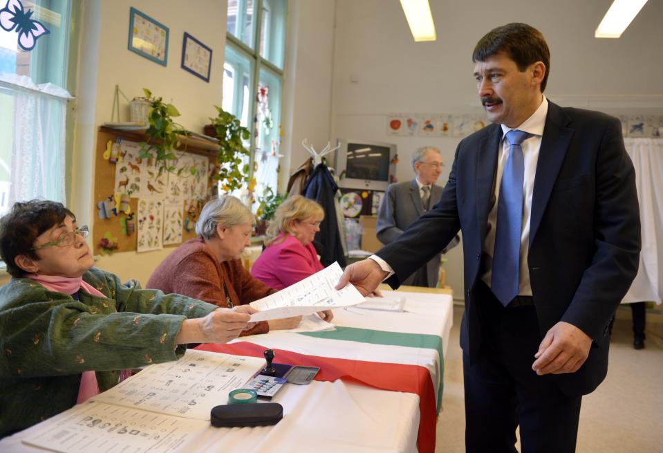 Hungarian President Janos Ader receives his ballot papers at a polling station in Budapest during the parliamentary elections in Hungary, Sunday, April 6, 2014. Hungary's governing party is tipped to win parliamentary elections Sunday, while a far-right party is expected to make further gains, according to polls. Prime Minister Viktor Orban's Fidesz party and its small ally, the Christian Democrats, are expected to win easily and they may even retain the two-thirds majority in the legislature gained in 2010 which allowed them to pass a new constitution, adopt unconventional economic policies, centralize power and grow the state's influence at the expense of the private sector. (AP Photo/MTI,Laszlo Beliczay)