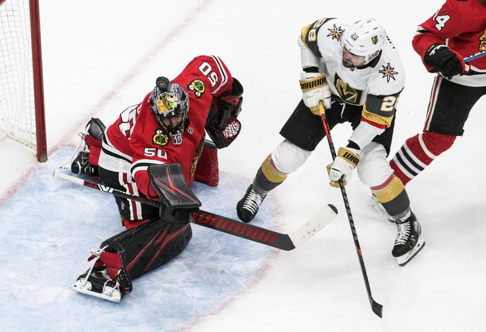 Vegas Golden Knights' William Carrier (28) is stopped by Chicago Blackhawks goalie Corey Crawford (50) who saves the puck with his helmet during first-period NHL Western Conference Stanley Cup playoff hockey action in Edmonton, Alberta, Sunday, Aug. 16, 2020. (Jason Franson/The Canadian Press via AP)