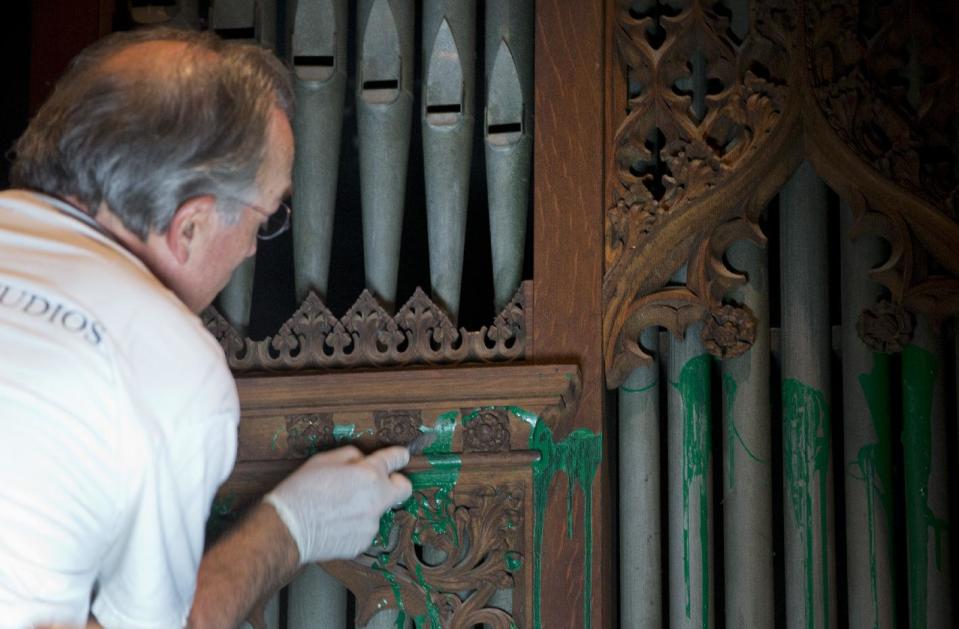 William Adair of Gold Leaf Studios remove green paint from the organ in the Washington National Cathedral's historic Bethlehem Chapel, Tuesday, July 30, 2013, in Washington. Officials at the cathedral discovered the paint inside two chapels Monday afternoon. The paint was splashed onto the organ and on the floor inside the Bethlehem Chapel on the basement level and inside Children's Chapel in the nave of the cathedral. (AP Photo/Carolyn Kaster)