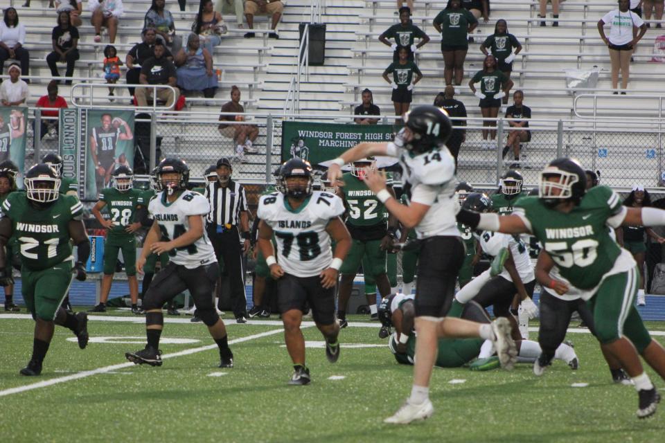 Islands quarterback Chet Bachman unleashes a long completion to Carson Curdys with Windsor Forest's Kendall Carter closing in Thursday night.