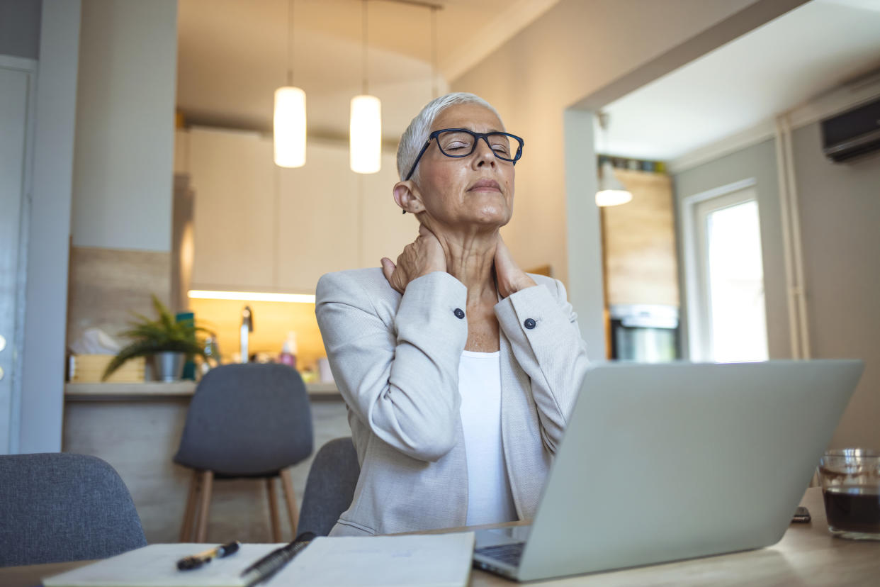 Woman in pain and hot due to menopause, trying to work. (Getty Images)