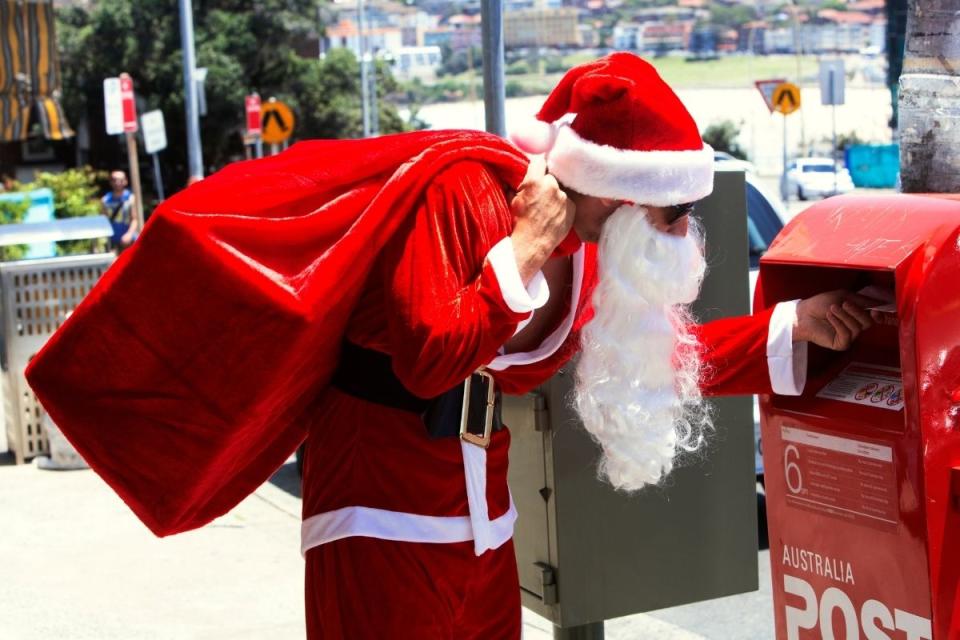 Man dressed as Santa delivers a letter to an Australia Post box. Source: Getty Images