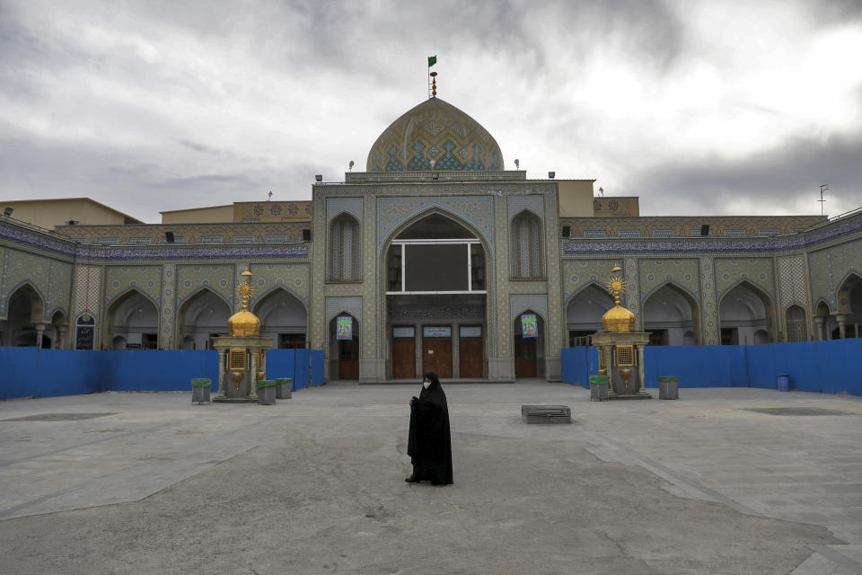 FILE - In this Saturday, March 7, 2020 file photo, a woman with a mask walks in the yard of a Friday prayer mosque in Shahr-e-Ray, south of Tehran, Iran. The typically frenetic streets of Iran's capital, Tehran, have fallen silent and empty due to the new coronavirus outbreak that's gripped the Islamic Republic. (AP Photo/Ebrahim Noroozi, File)