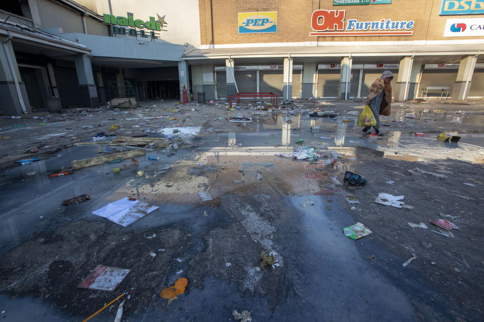 A young girl carrying groceries looted from a nearby shop, walks back home at Naledi shopping complex in Vosloorus, east of Johannesburg, South Africa, Monday, July 12, 2021. Police say six people are dead and more than 200 have been arrested amid escalating violence during rioting that broke out following the imprisonment of South Africa's former President Jacob Zuma. (AP Photo/Themba Hadebe)