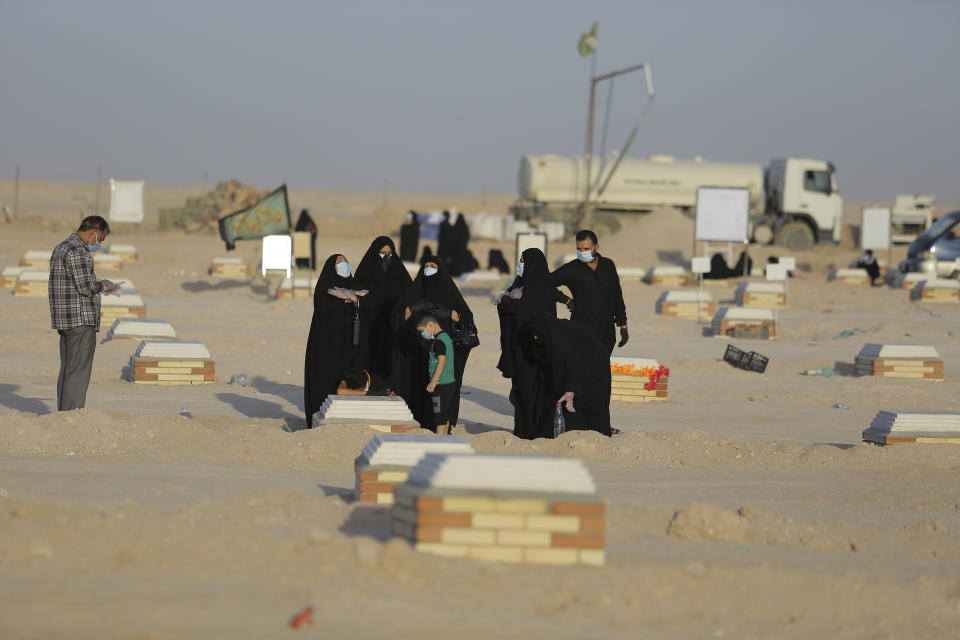 Family visits a grave of a coronavirus victim at Wadi al-Salam cemetery near Najaf, Iraq, Monday, July 20, 2020. A special burial ground near the Wadi al-Salam cemetery has been created specifically for COVID-19 victims since rejections of such burials have continued in Baghdad cemeteries and elsewhere in Iraq. (AP Photo/Anmar Khalil)