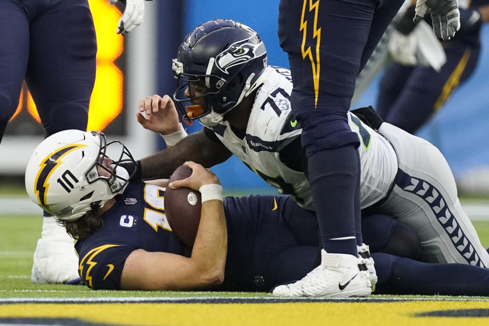 Los Angeles Chargers quarterback Justin Herbert (10) is sacked by Seattle Seahawks defensive tackle Quinton Jefferson (77) during the second half of an NFL football game Sunday, Oct. 23, 2022, in Inglewood, Calif. (AP Photo/Mark J. Terrill)