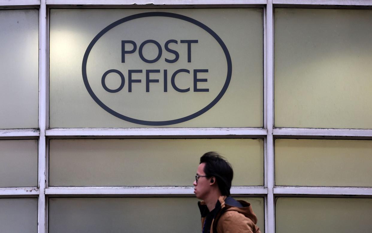 A pedestrian passes a Post Office in London