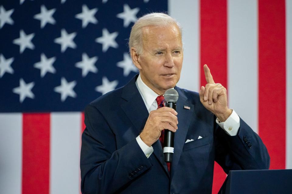 President Biden delivering remarks while standing in front of a large American flag.