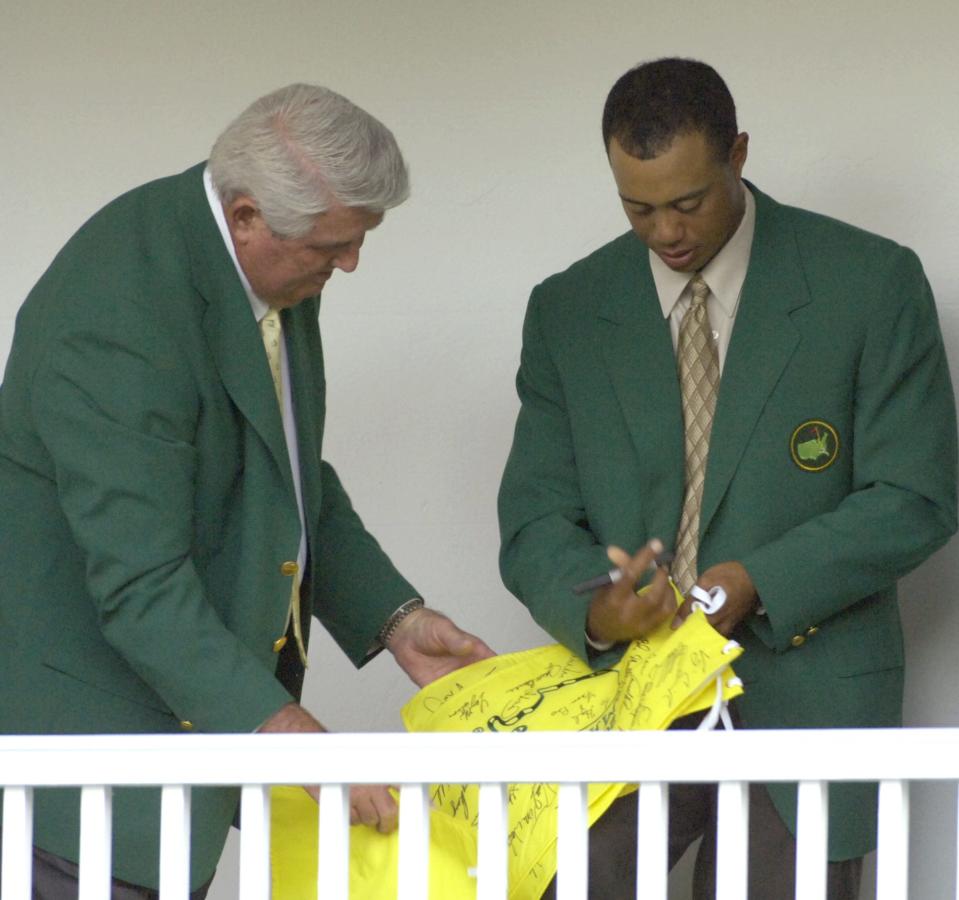 Tiger Woods (right) signs a flag for fellow Masters champion Charles Coody before the 2006 Champions Dinner at Augusta National Golf Club.