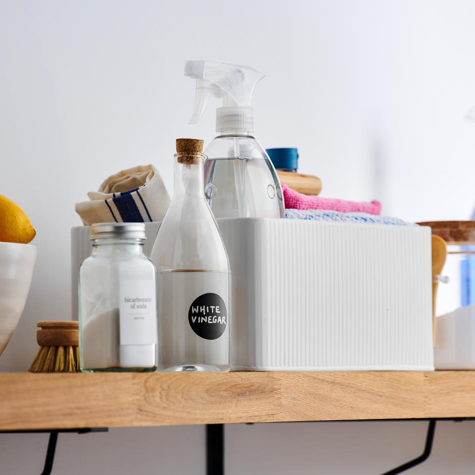  Open shelf used to store cleaning supplies and a cleaning caddy. 