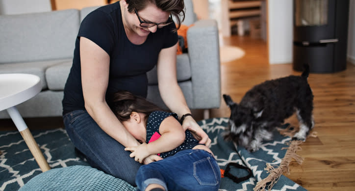 A little girl is tickled by her mum.