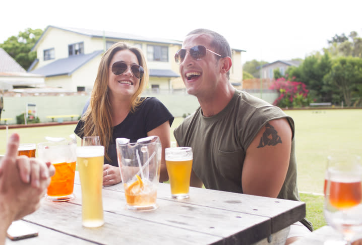 A young couple are pictured drinking beer at a lawn bowls club.