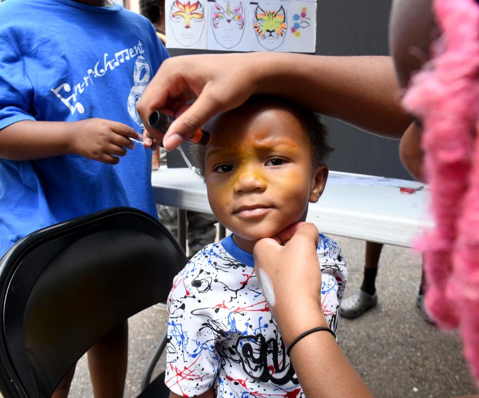 Amir Jackson 3, of Canton gets his face painted Friday by Payton Finley, 16, of Plain Township at EN-RICH-MENT'S third annual African American Arts Festival at Centennial Plaza in Canton.