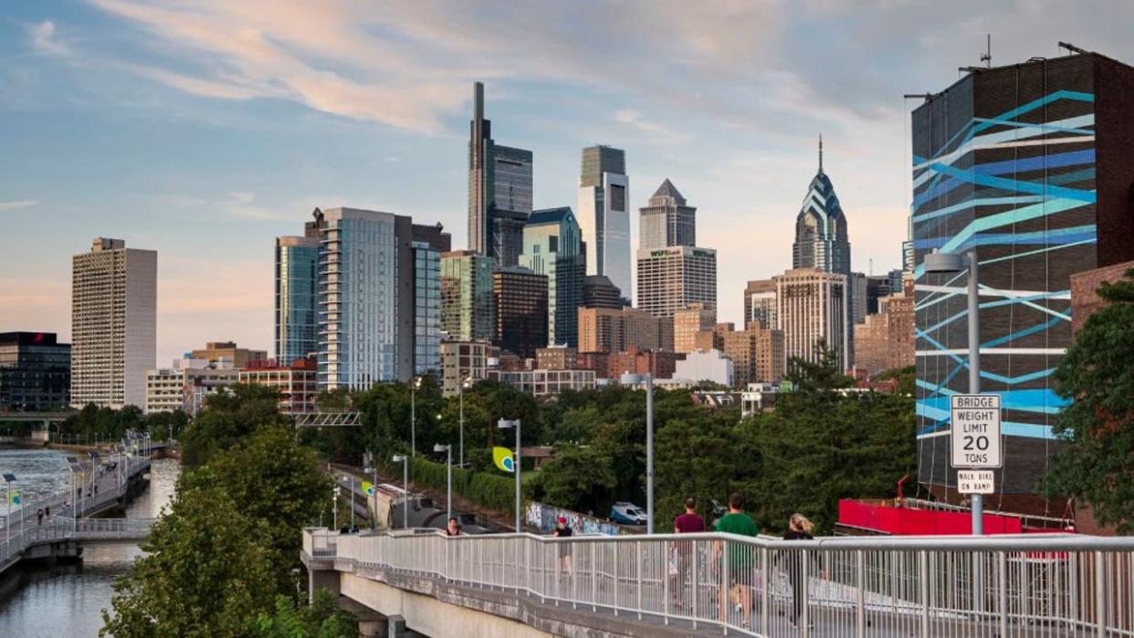 <div>People of Pedestrian Bridge with Skyline with Schuylkill River Boardwalk at sunset, Philadelphia, Pennsylvania, USA. (Photo by: Jumping Rocks/UCG/Universal Images Group via Getty Images)</div>