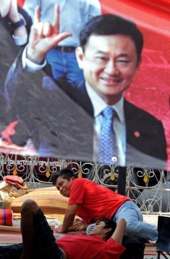 Red Shirt supporters of ousted premier Thaksin Shinawatra rest under a poster of him in Bangkok in March 2010. Thailand's Prime Minister Abhisit Vejjajiva has said he will ask the king to dissolve parliament for the country's first general election since deadly political violence rocked Bangkok last year
