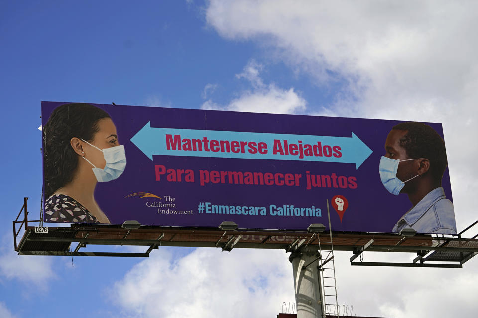 A giant banner reads in Spanish, "Stay Apart to Stay Together," in Los Angeles Monday, Jan. 25, 2021. California has lifted regional stay-at-home orders statewide in response to improving coronavirus conditions. Public health officials said Monday that the state will return to a system of county-by-county restrictions intended to stem the spread of the virus. Local officials could choose to continue stricter rules. The state is also lifting a 10 p.m. to 5 a.m. curfew. (AP Photo/Damian Dovarganes)