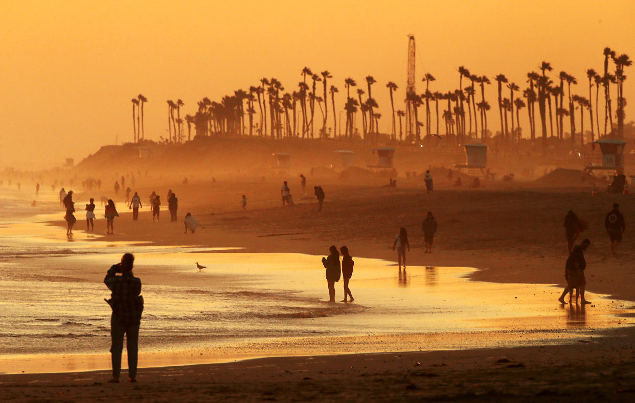 Beachgoers on a beach at sunset.