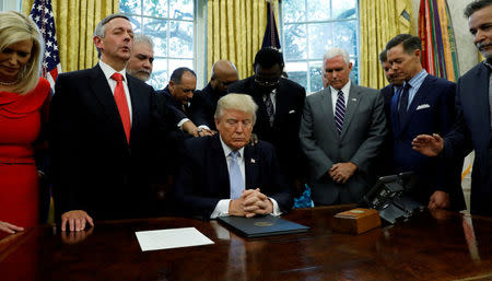 FILE PHOTO: Faith leaders place their hands on the shoulders of U.S. President Donald Trump as he takes part in a prayer for those affected by Hurricane Harvey in the Oval Office of the White House in Washington, U.S., September 1, 2017. REUTERS/Kevin Lamarque/Files