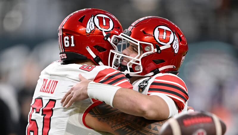 Utah Utes offensive lineman Kolinu'u Faaiu (61) and Utah Utes quarterback Bryson Barnes (16) hug as Utah and Northwestern prepare to play in the SRS Distribution Las Vegas Bowl on Saturday, Dec. 23, 2023.