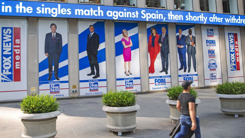 A man walks past promotional posters outside Fox News studios at News Corporation headquarters in New York on Saturday, July 31, 2021. From left to right are hosts Tucker Carlson, Sean Hannity, Laura Ingraham, Maria Bartiromo, Stuart Varney, Neil Cavuto and Charles Payne.