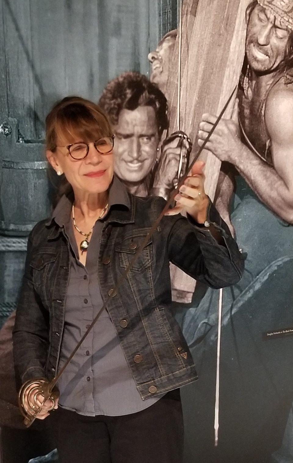 Exhibit designer, Elizabeth Skrabonja holds one of Douglas Fairbanks' swords.