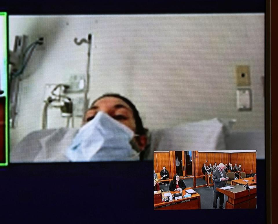 In this video screen image, Lindsay Clancy with a surgical mask over her face in a hospital appears during her arraignment (The Boston Globe)