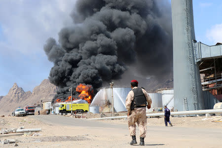A soldier walks as fire engulfs an oil storage tank at the Aden oil refinery one day after an explosion in the refinery in Aden, Yemen January 12, 2019. REUTERS/Fawaz Salman