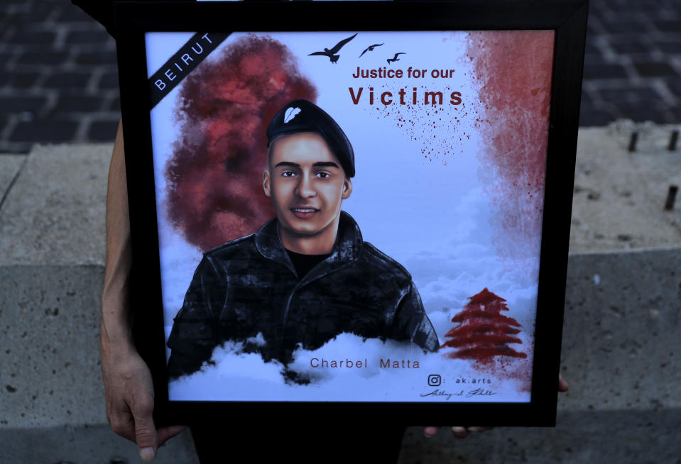 A relative of a firefighter who was killed in the massive blast last year at the Beirut port holds his portrait as she attends a sit-in at the main gate of the seaport, in Beirut, Lebanon, Monday, Oct. 4, 2021. Lebanon's appeals court on Monday rejected lawsuits filed against the lead investigator of the Beirut port explosion in a decision that allows him to resume his work, the country's National News agency said. (AP Photo/Hussein Malla)