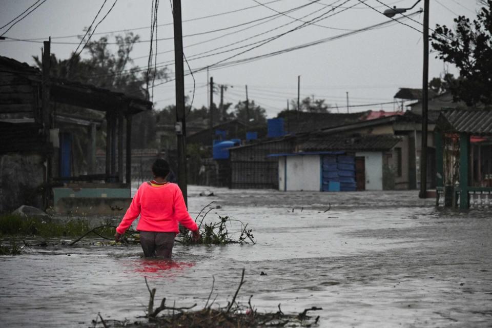 A woman walks through a flooded street in Batabano, Cuba, on Tuesday, during the passage of hurricane Ian. (AFP via Getty Images)