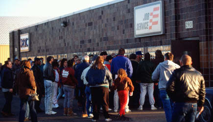 Jobless people waiting in line outside unemployment office.