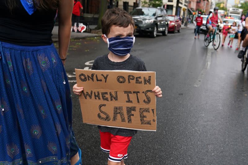 A child marches down Court St to protest the opening of schools