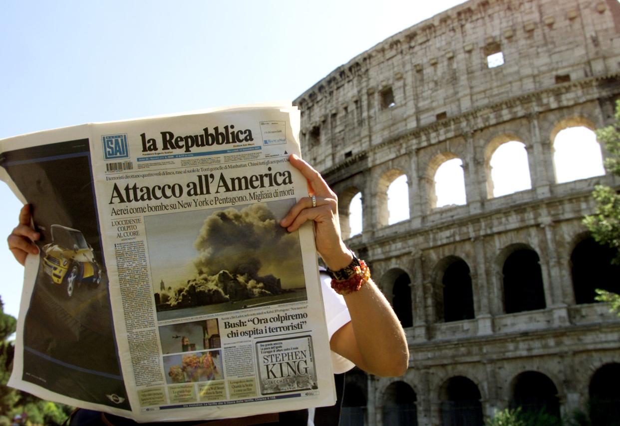 A woman reads about the terrorist attack on New York's World Trade Center with the Roman's ancient Colosseum in central Rome September 12, 2001. A saddened Pope John Paul on Wednesday condemned suicide attacks in the United States as a dark day in the history of humanity and urged the world not to allow a spiral of hate and violence to prevail.