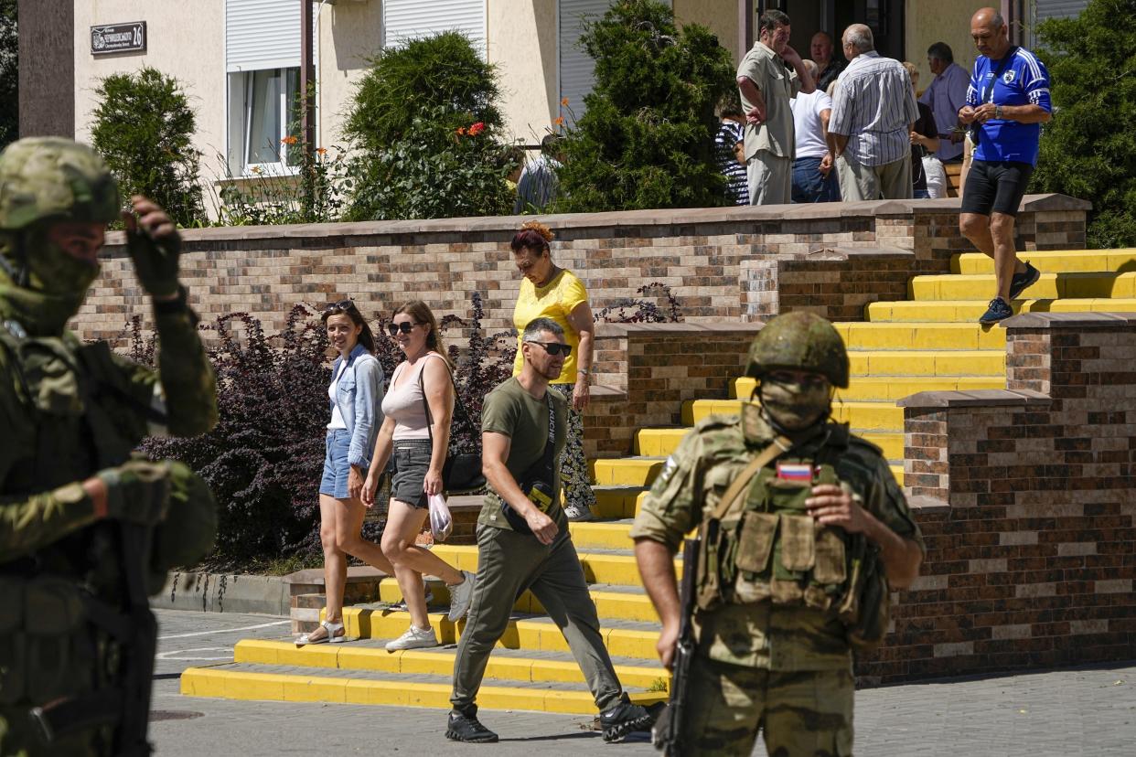 People walk past as Russian soldiers guard an office for Russian citizenship applications, in Melitopol, south Ukraine. Russia took control of part of the Zaporizhzhia region quickly after the launch of the military operation in Ukraine. (AP)