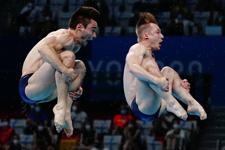 Two divers with their mouths open as they spin through the air