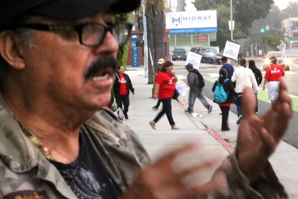 Jacinto Antonio Herrera, with fellow hotel workers picketing in background.