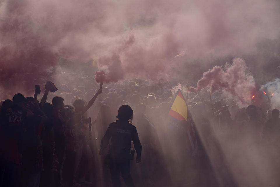 Police officers stand guard as supporters burn flares outside the Metropolitano stadium, ahead of the Champions League quarterfinal first leg soccer match between Atletico de Madrid and Dortmund in Madrid, Spain, Wednesday, April 10, 2024. This week's Champions League soccer games will go ahead as scheduled despite an Islamic State terror threat. A media outlet linked to the terror group has issued multiple posts calling for attacks at the stadiums hosting quarterfinal matches in Paris, Madrid and London. (AP Photo/Andrea Comas)