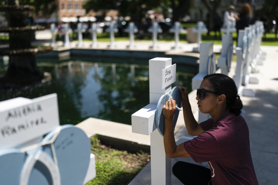 A women, who declined to give her name, writes a message at a memorial site for Jose Flores, one of the Robb Elementary School shooting victims, in Uvalde, Texas, Thursday, May 26, 2022. (AP Photo/Jae C. Hong)