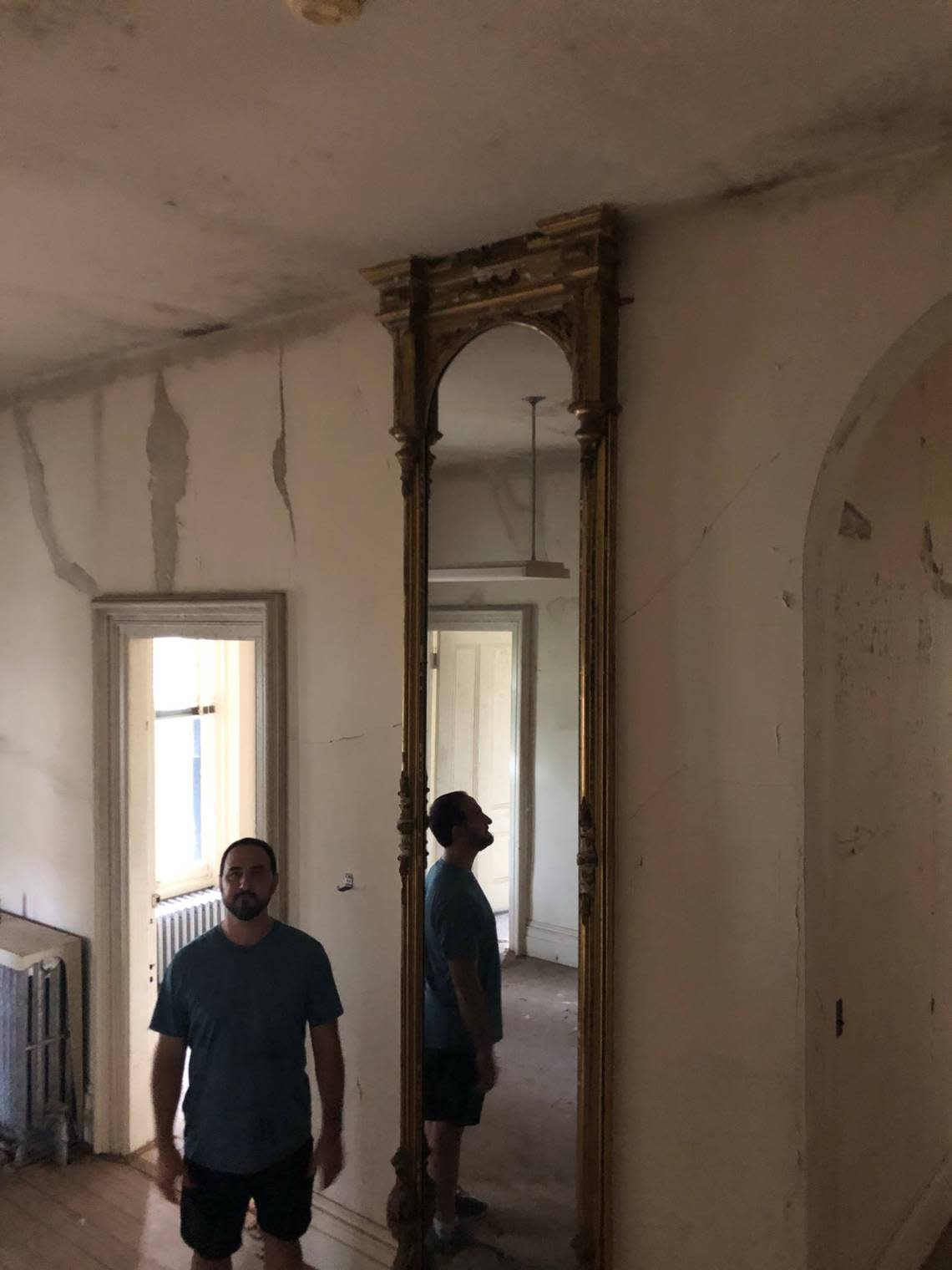 Jeff Turpin stands in the entryway next to a mirror that is original to the house prior to renovations.
