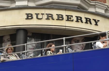 Visitors on an open-top tour bus drive past a Burberry store in central London, Britain July 15, 2015. REUTERS/Toby Melville