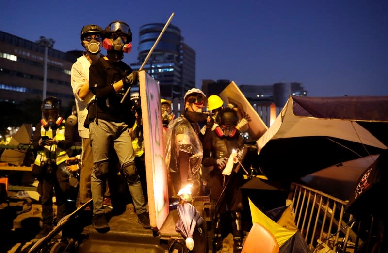 Anti-government protesters wear gas masks during clashes with police, outside Hong Kong Polytechnic University