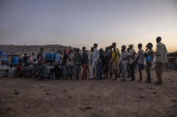 Tigray men who fled the conflict in Ethiopia's Tigray region, stand in line to receive food cooked by Sudanese women volunteers, at Umm Rakouba refugee camp in Qadarif, eastern Sudan, Thursday, Nov. 26, 2020. Ethiopia's prime minister said Thursday the army has been ordered to move on the embattled Tigray regional capital after his 72-hour ultimatum ended for Tigray leaders to surrender, and he warned the city's half-million residents to stay indoors and disarm. (AP Photo/Nariman El-Mofty)