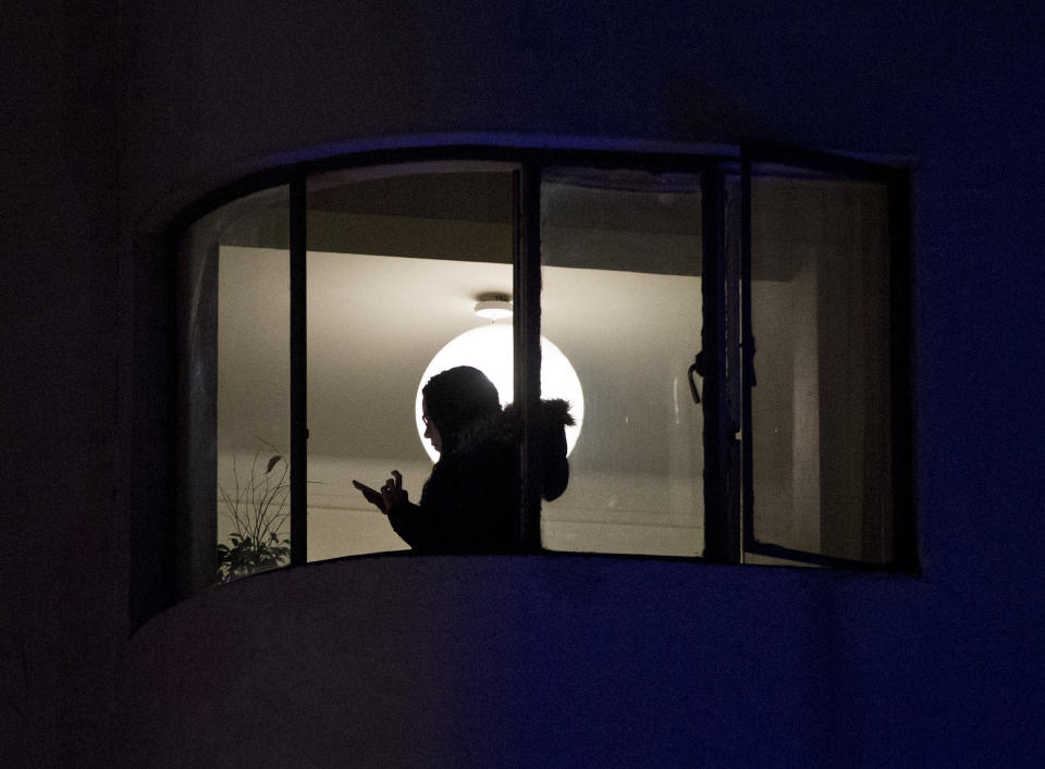 In this Wednesday, May 22, 2019 photo, a woman communicates on her mobile phone next to an apartment where six Brazilians died of carbon monoxide poisoning in Santiago, Chile. Police commander Rodrigo Soto said officers found four adults and two children dead at the six-story building. (AP Photo/Esteban Felix)